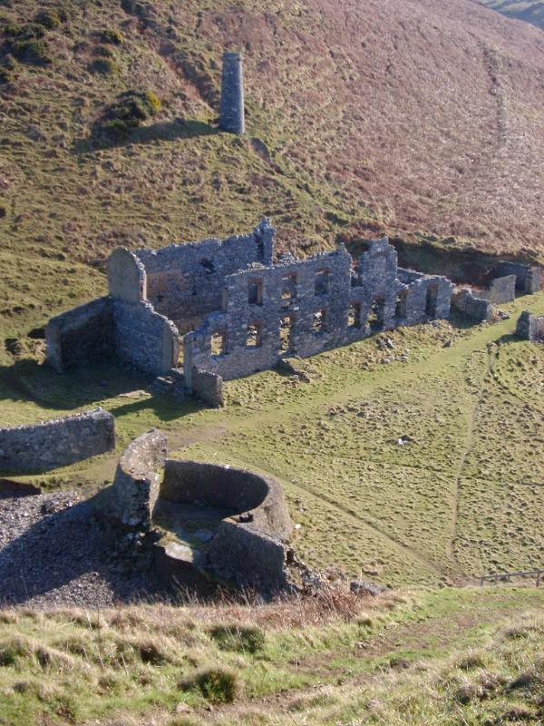 Ruins of an old factory with stone walls and an old iron smelter viewed high angle in a valley