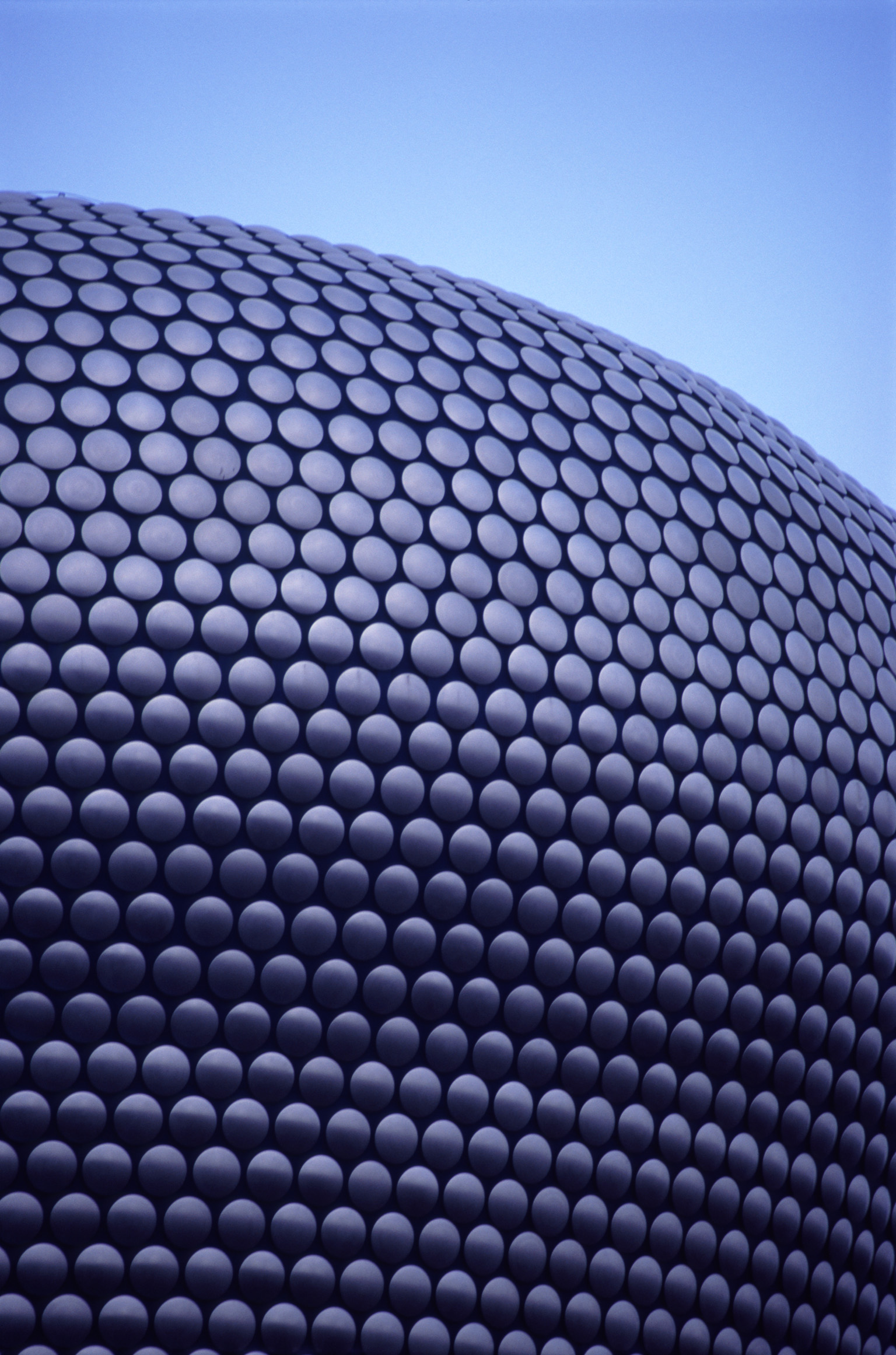 an image of Exterior of the new Bullring Shopping Centre, Birmingham with its distinctive curved architectural design against a blue sky