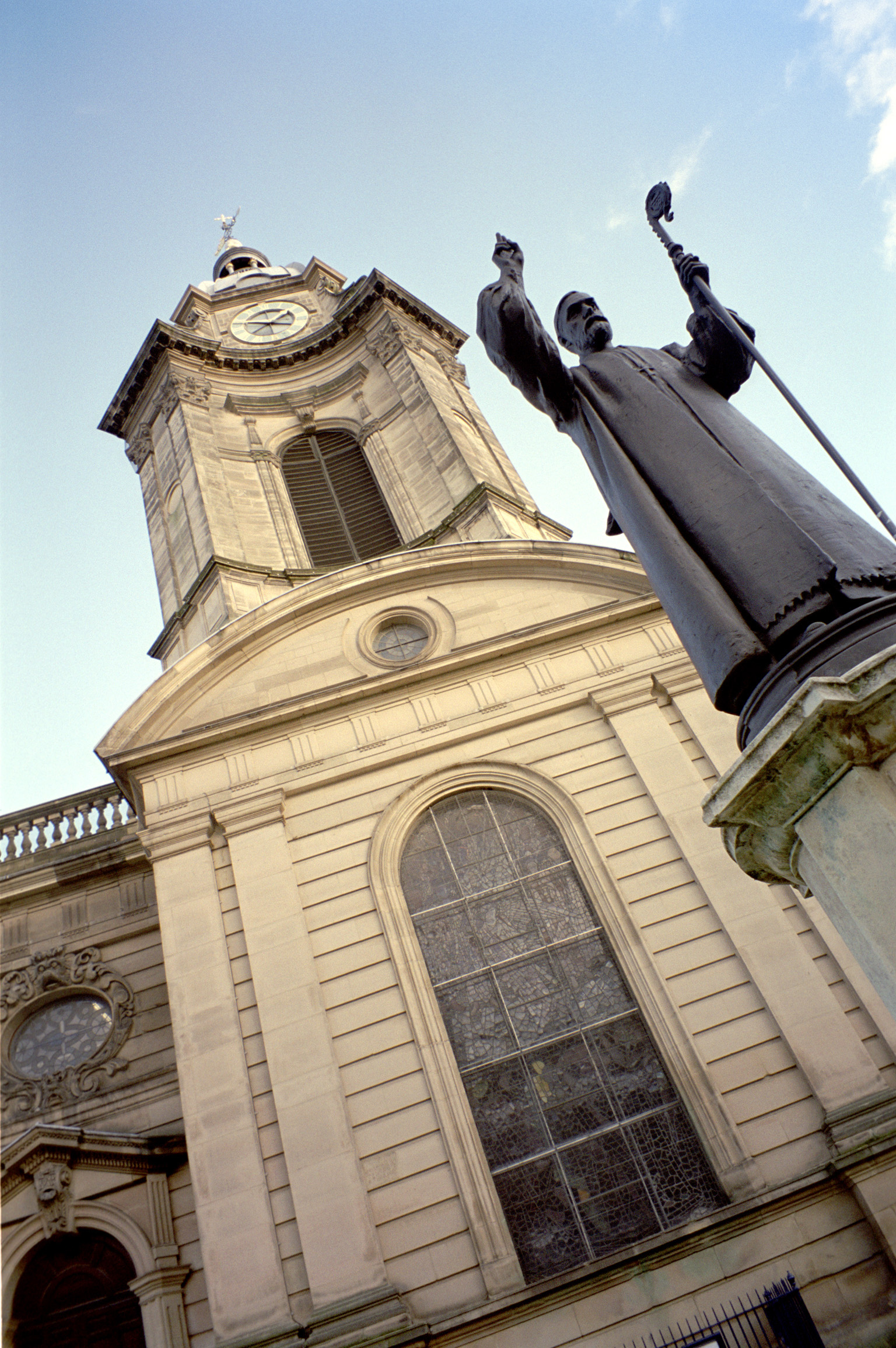 an image of Birmingham library detail with a low angle view of an ecclesiastical statue and arched window against a blue sky