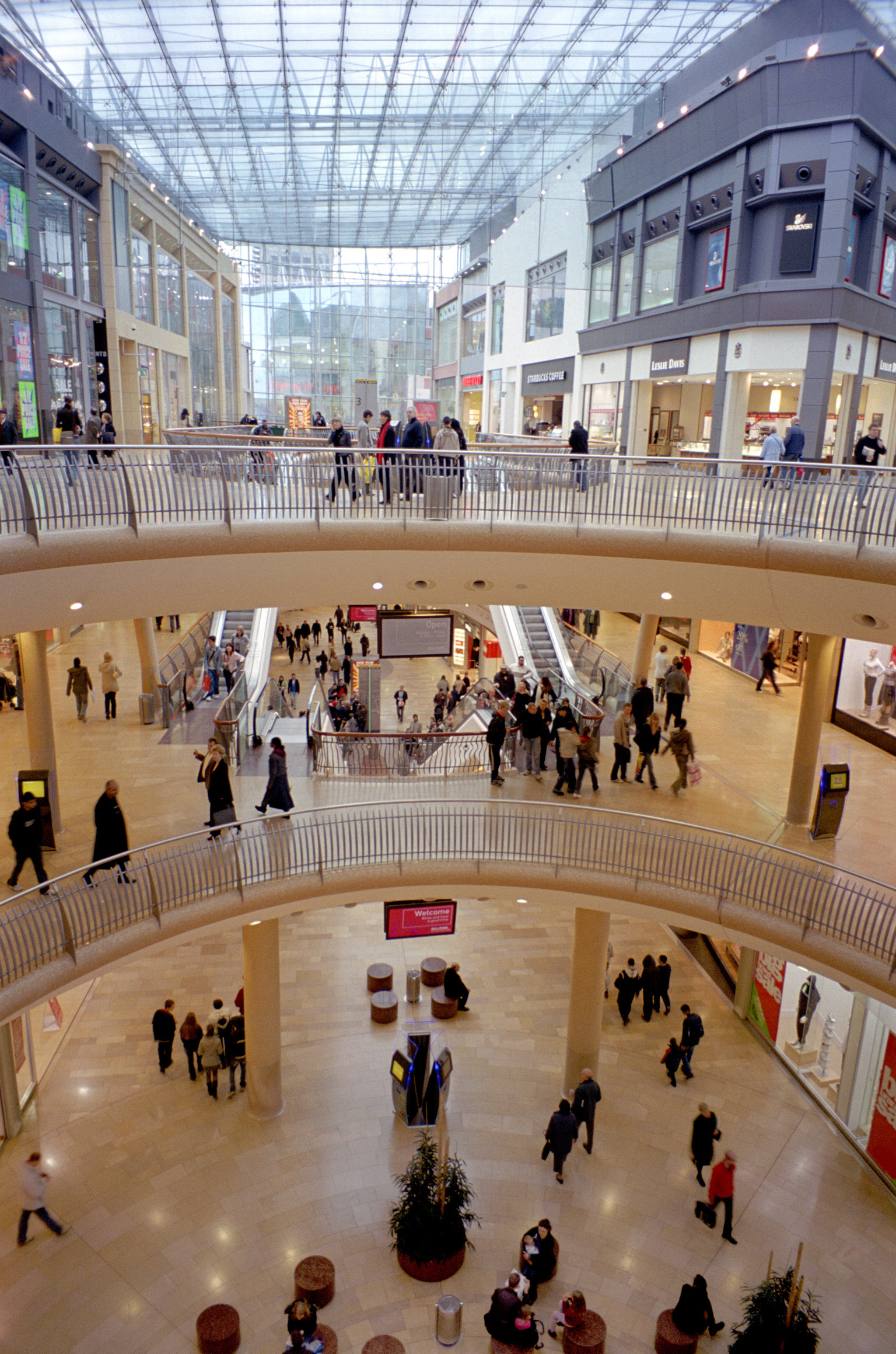 an image of Inside the new Bullring shopping centre in Birmingham showing various walkways with groups of shoppers and a variety of stores