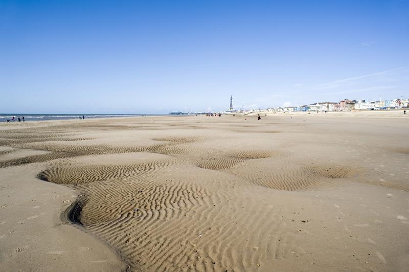 a panoramic view of blackpool sands at low tide with the tower andd central pier in the distance.