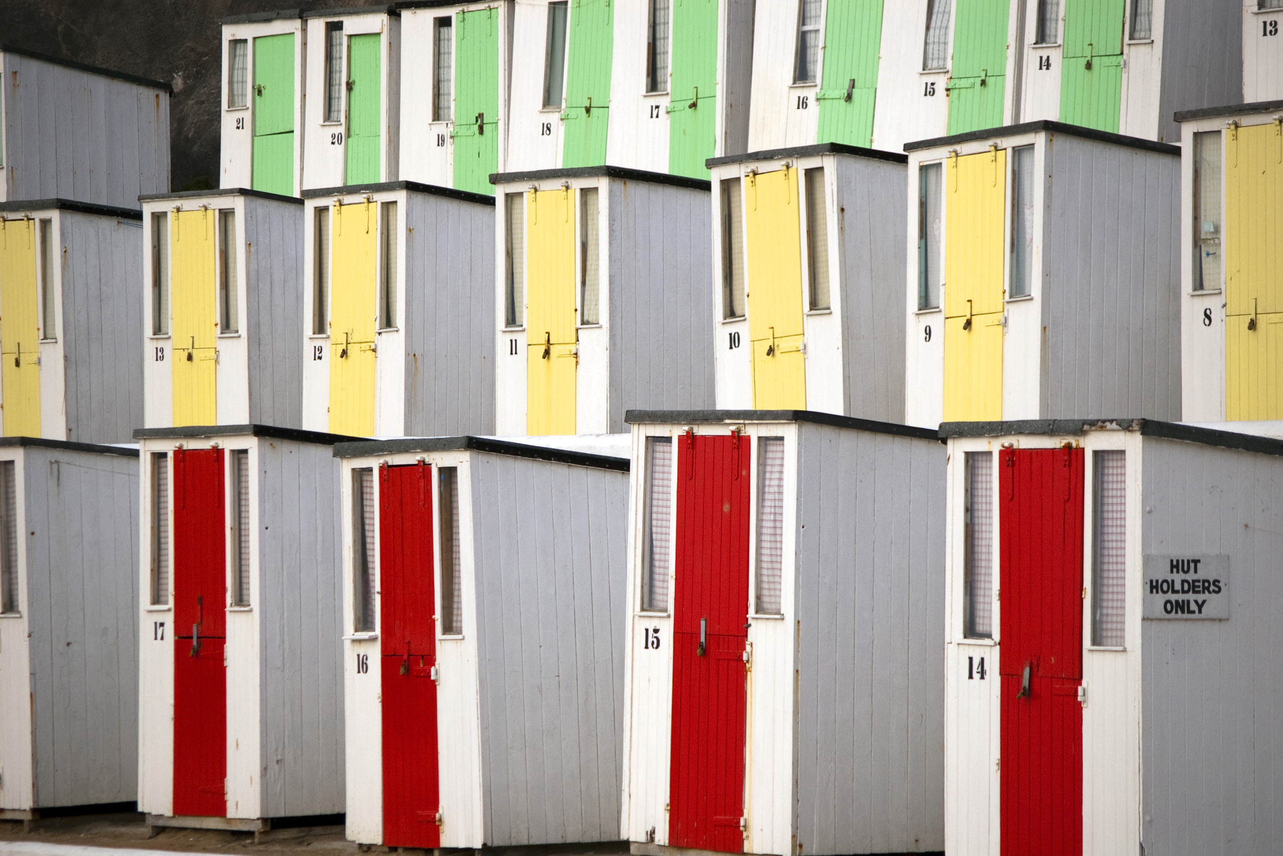 an image of rows of beach huts at newquay with brightly painted doors