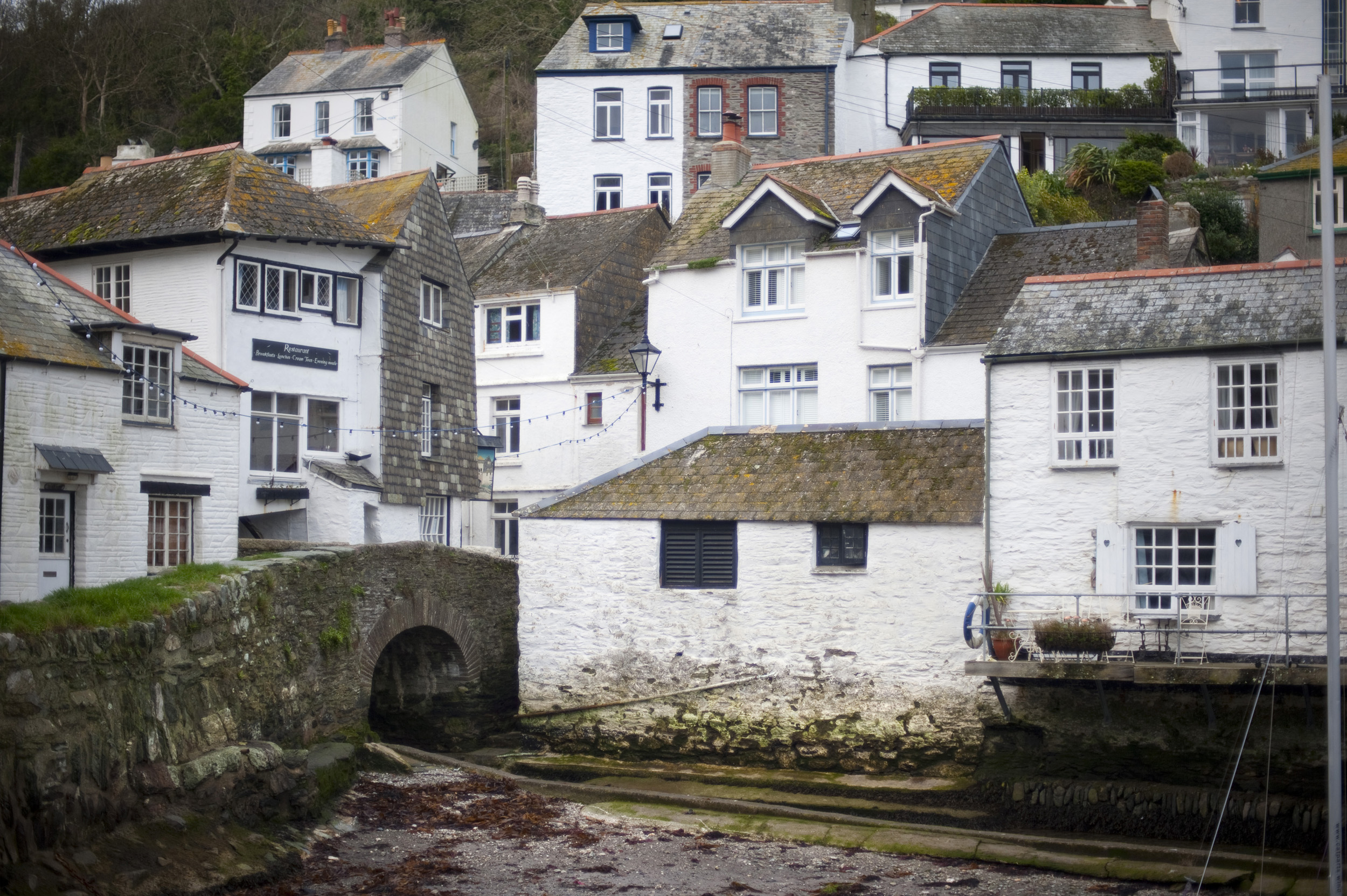 an image of white painted houses cling to the hillside in polperro