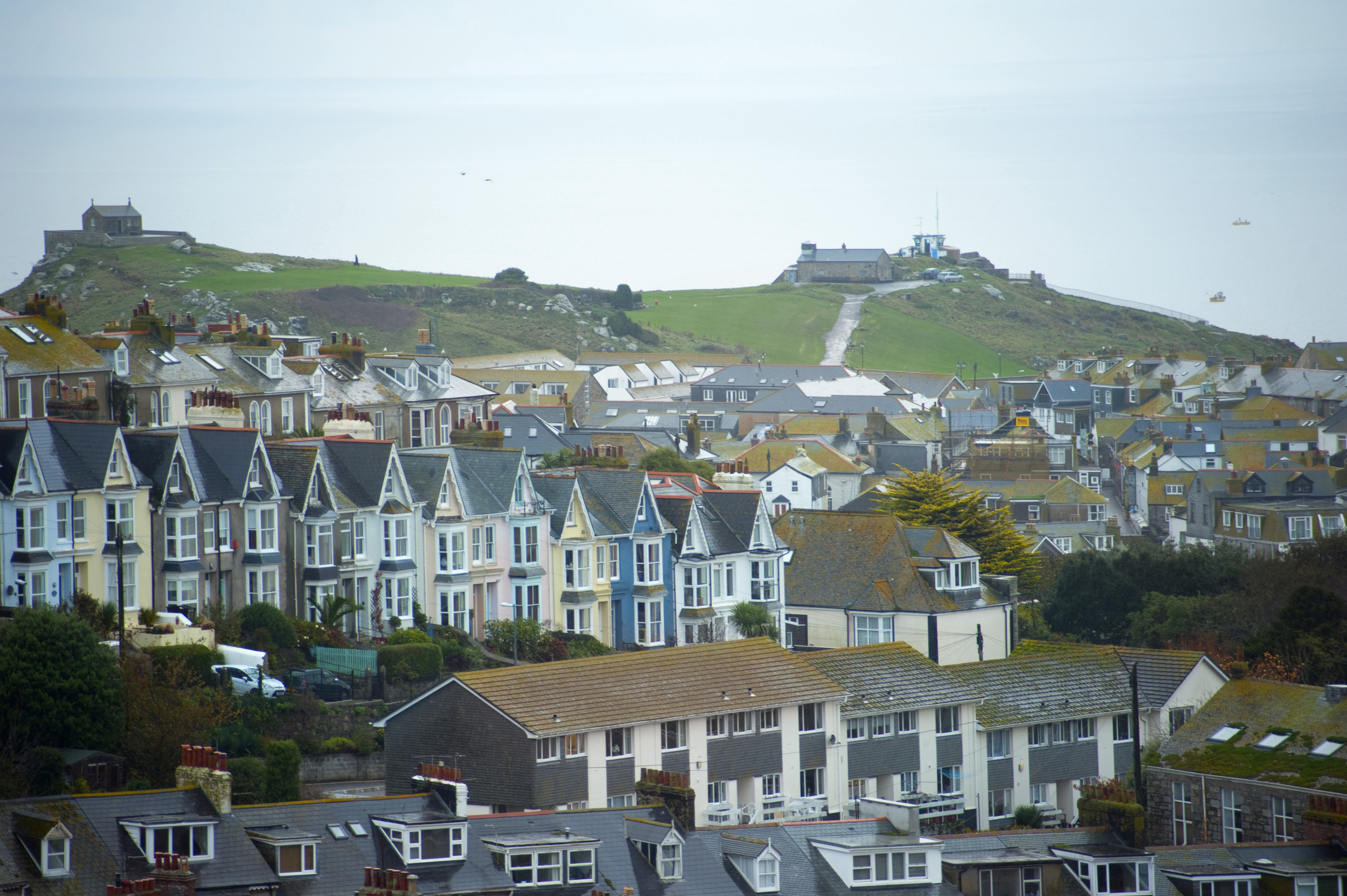 an image of rows of old and new houses in the cornish town of st ives, Chapel of St Nicholas and the watch station in the distance on a part of town known as The Island