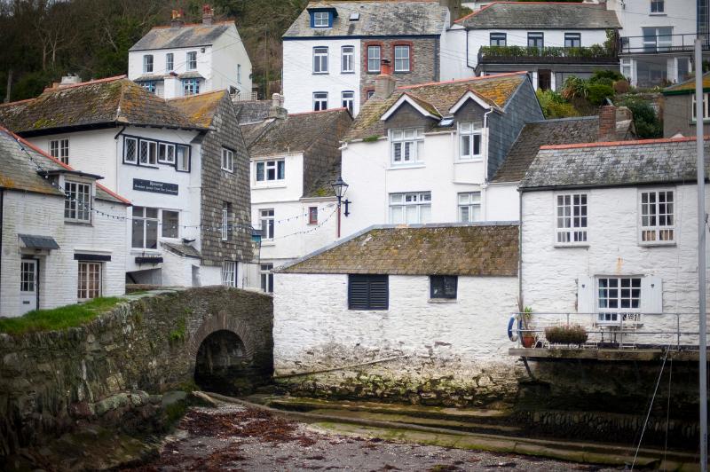 white painted houses cling to the hillside in polperro