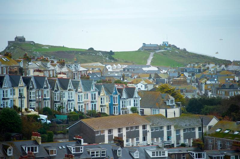 rows of old and new houses in the cornish town of st ives, Chapel of St Nicholas and the watch station in the distance on a part of town known as The Island
