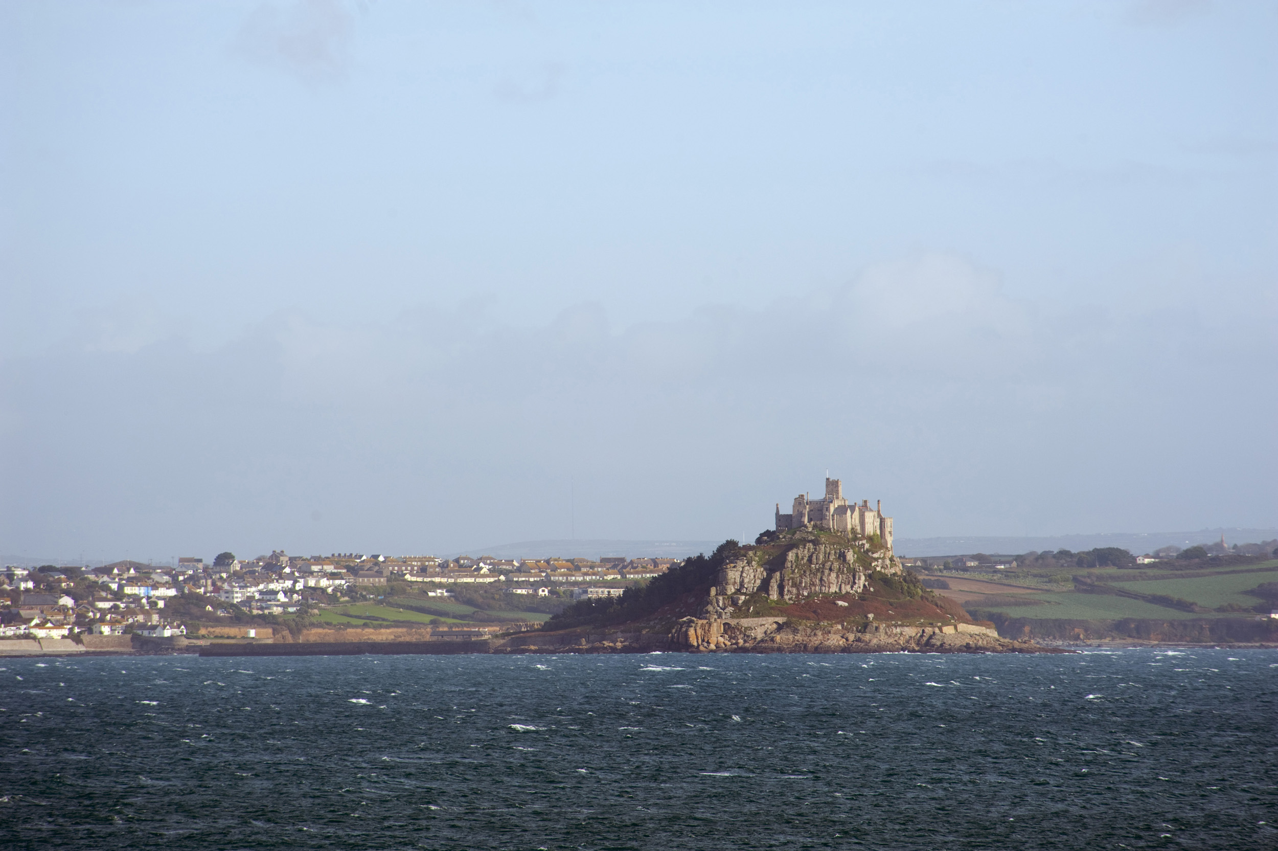 an image of a view of the back of saint michaels mount taken from across the water and town of marazion