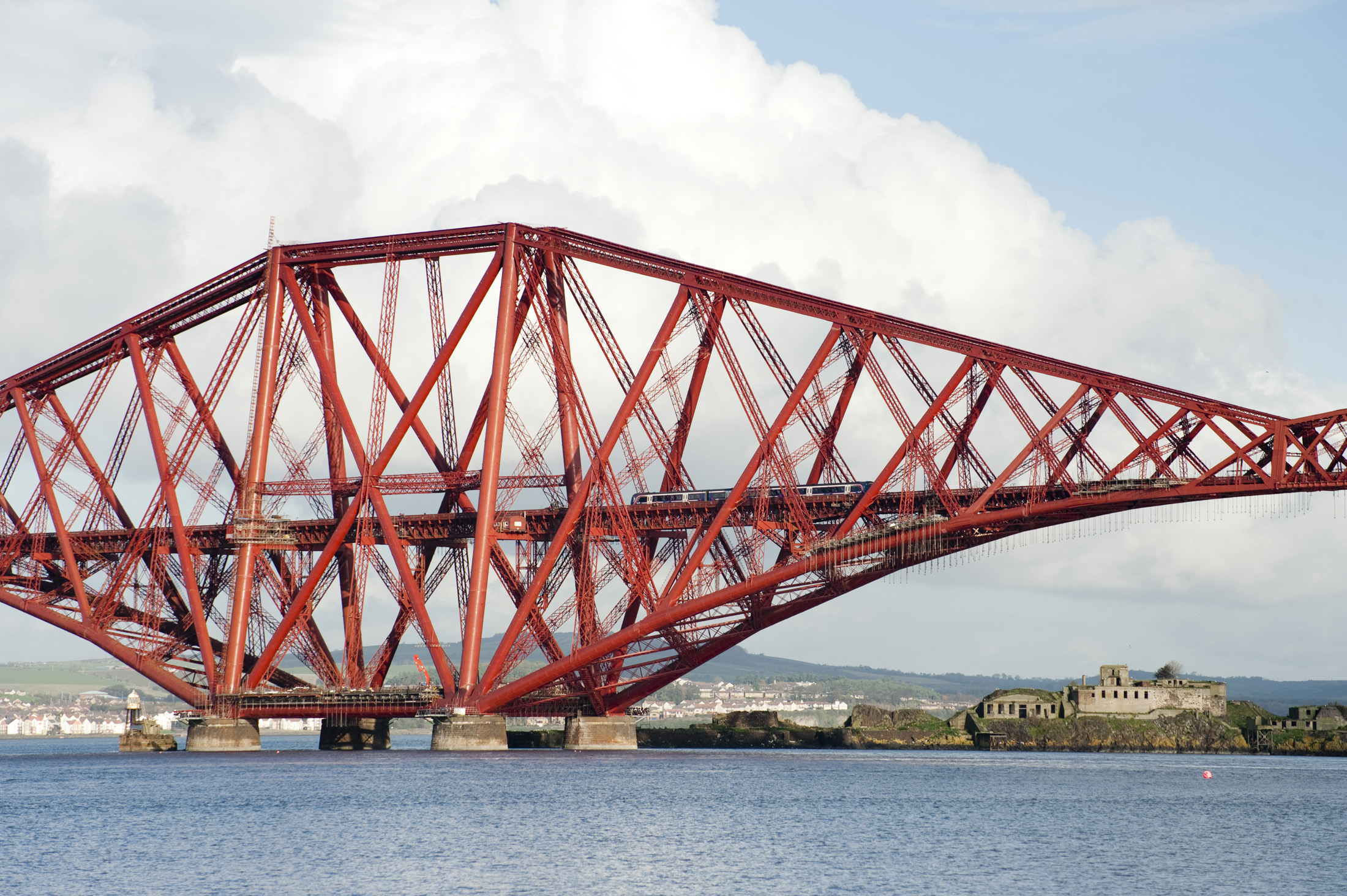 an image of a train dwarfed by the giant structure of the forth bridge, firth of forth, scotland