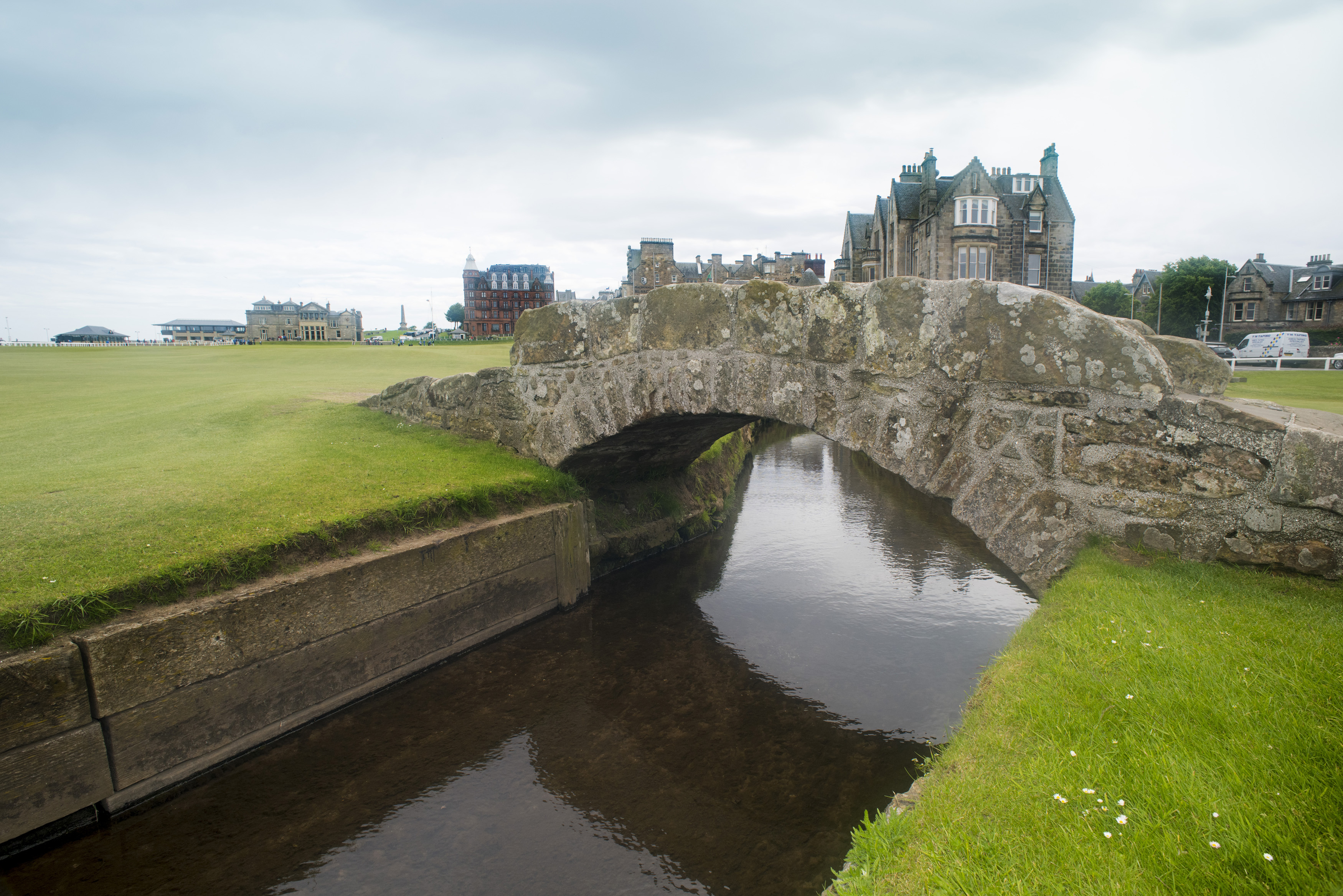 an image of Close up view of the picturesque stone Swilken Bridge, St Andrews Golf Course , Scotland with the town visible in the distance across the green fairways