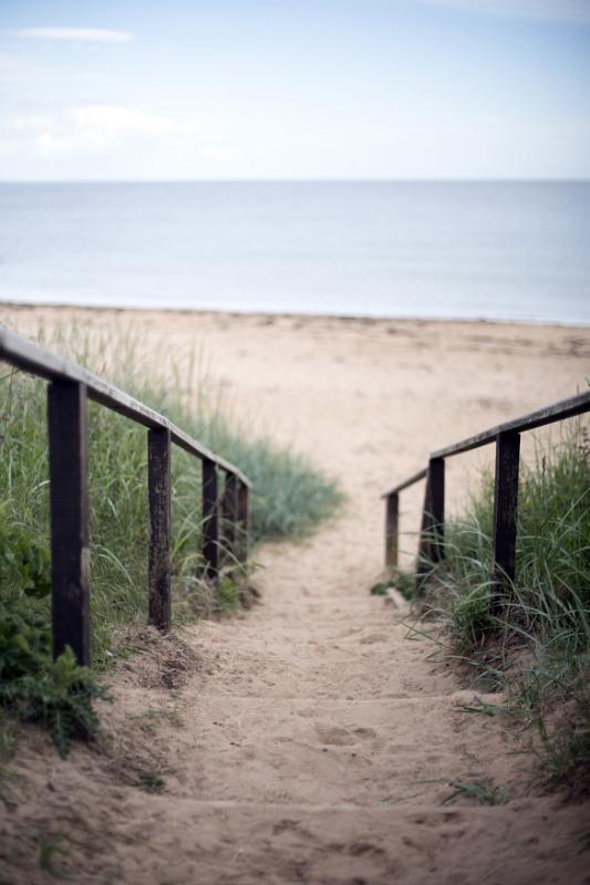 Steps leading down to a sandy beach on the Fife coast of Scotland in a receding view