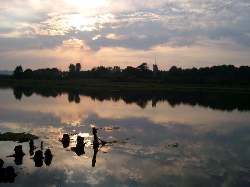River Yar near Freshwater at sunset with the trees and a church reflected in the calm water
