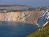 View along the scenic coastline of the Alum Bay cliffs, Isle of Wight showing erosion of color of the chalk with a calm ocean below
