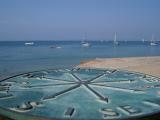 metal plaque marking the points of the compass with yachts on the water in the background