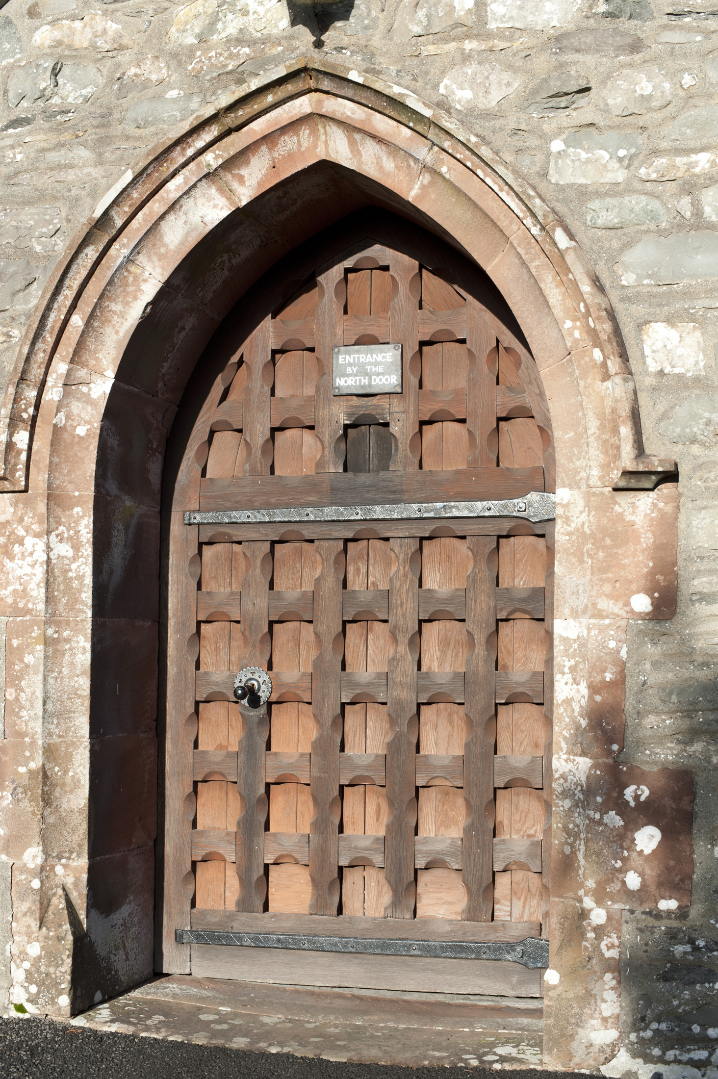 an image of Arched medieval wooden entrance door to St Michaels and All Angels Church in the village of Hawkshead in the Lake District in Cumbria
