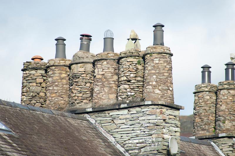 Row of rooftop cylindrical stone chimney pots on a cottage in Skelwith Bridge in the English Lake Distict