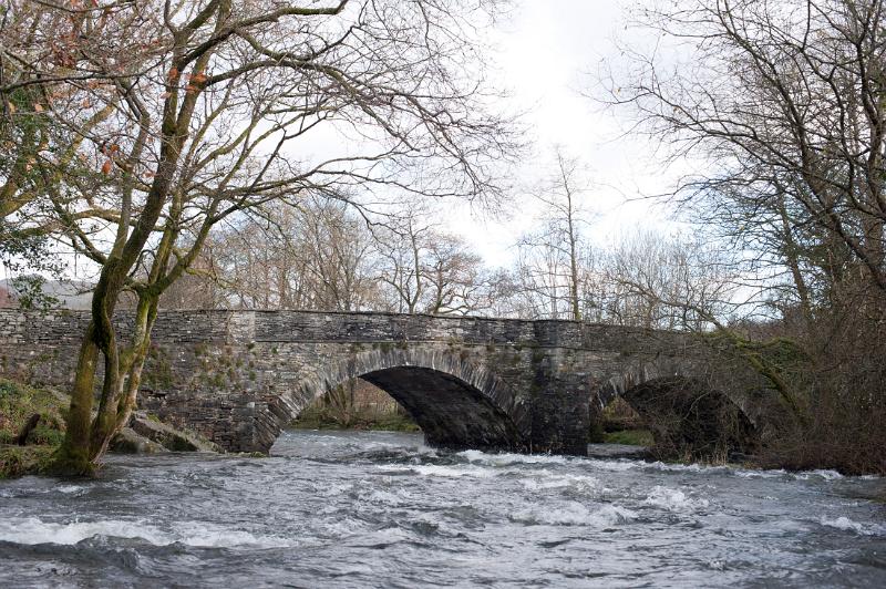 View of the historical stone arches of Skelwith Bridge in the Lake District in Cumbria with the river flowing in full spate