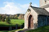 Stone entrance to Hawkshead church in the Lake District in Cumbria with a view to livestock grazing in the lush green pastures of the Lake District