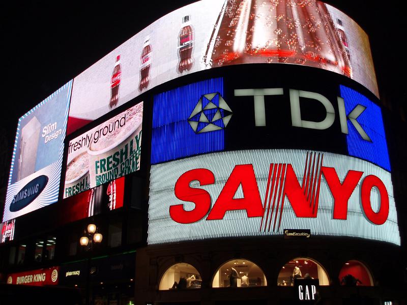 Bright neon advertising signs illuminated at night in Piccadilly Circus, London on the exterior of a curved building