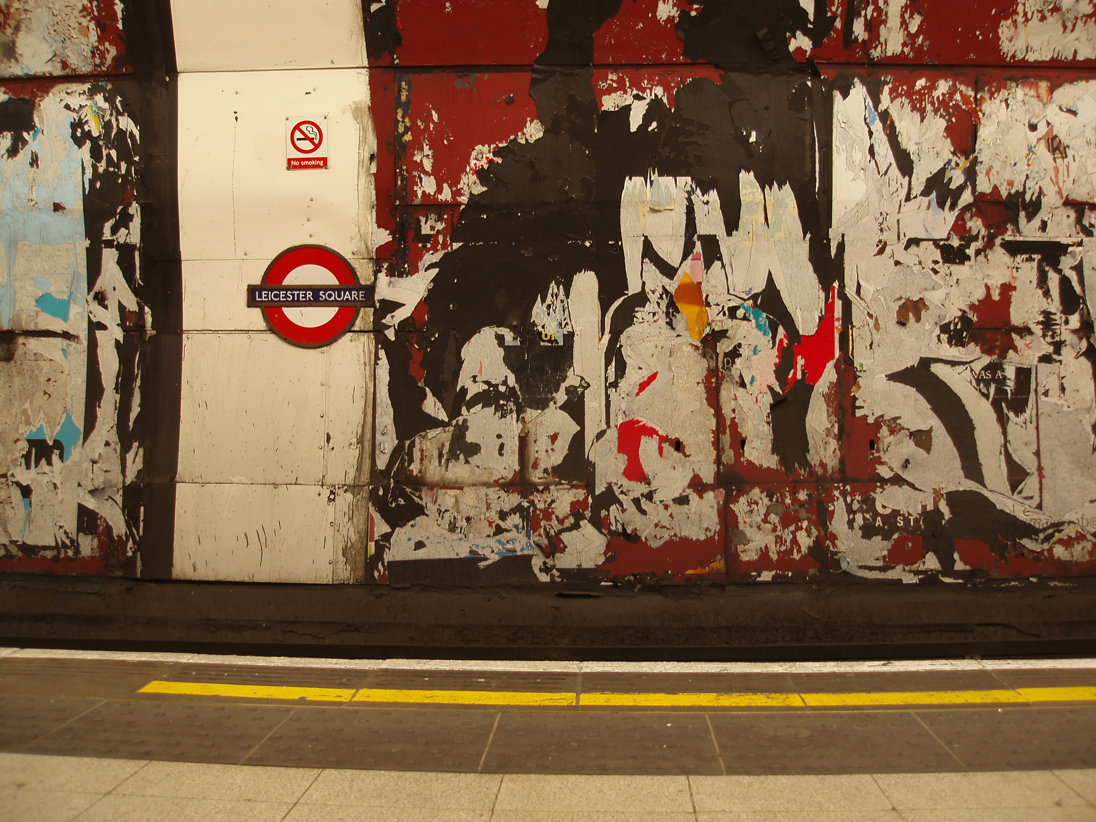 an image of Grungy walls on the platform at the tune station London underground with remnants of posters and advertising and flaking paint