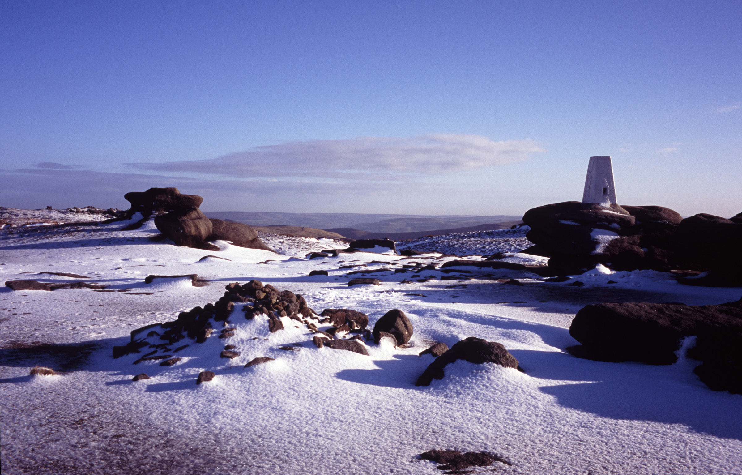 an image of Picturesque view of the Kinder Scout moorlands in winter snow under a sunny crisp blue sky