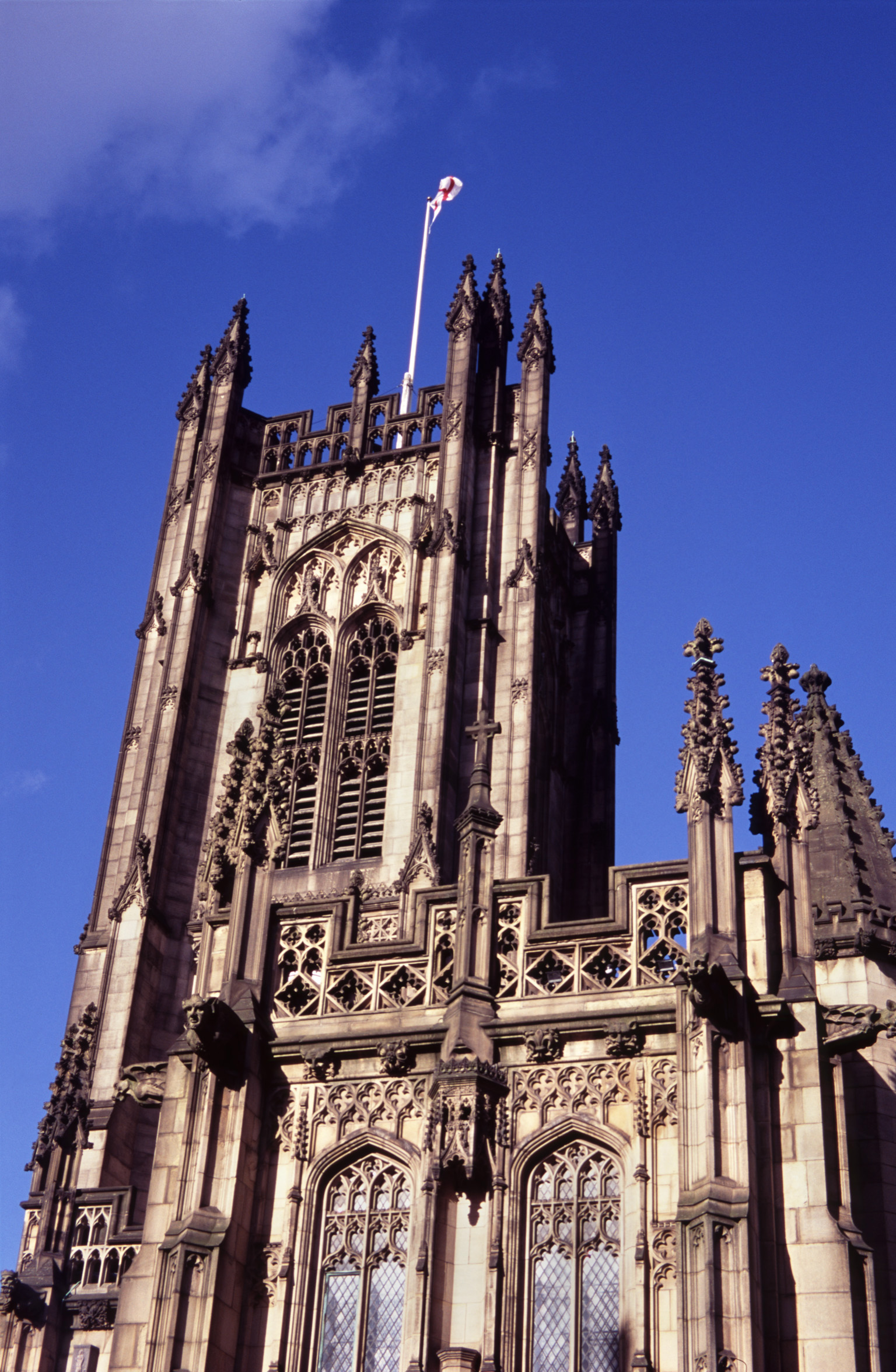 an image of Exterior View of Upper Part of Historic Manchester Cathedral in England, United Kingdom. Captured with Light Blue Violet Sky Background.