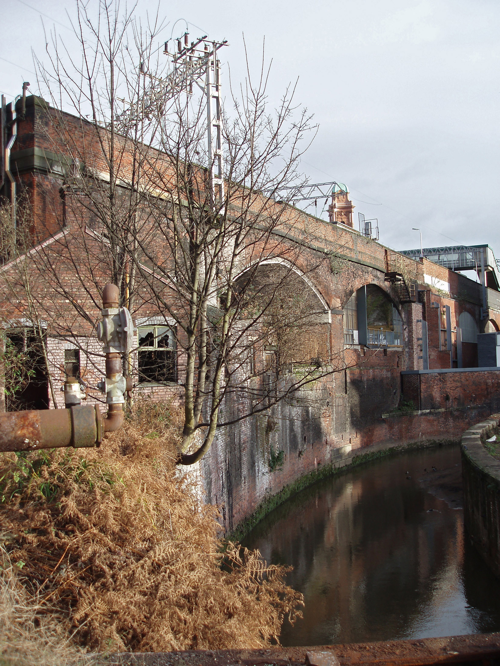 an image of Central Manchester industrial canals bordered by the rundown arches of a railway and old warehouses