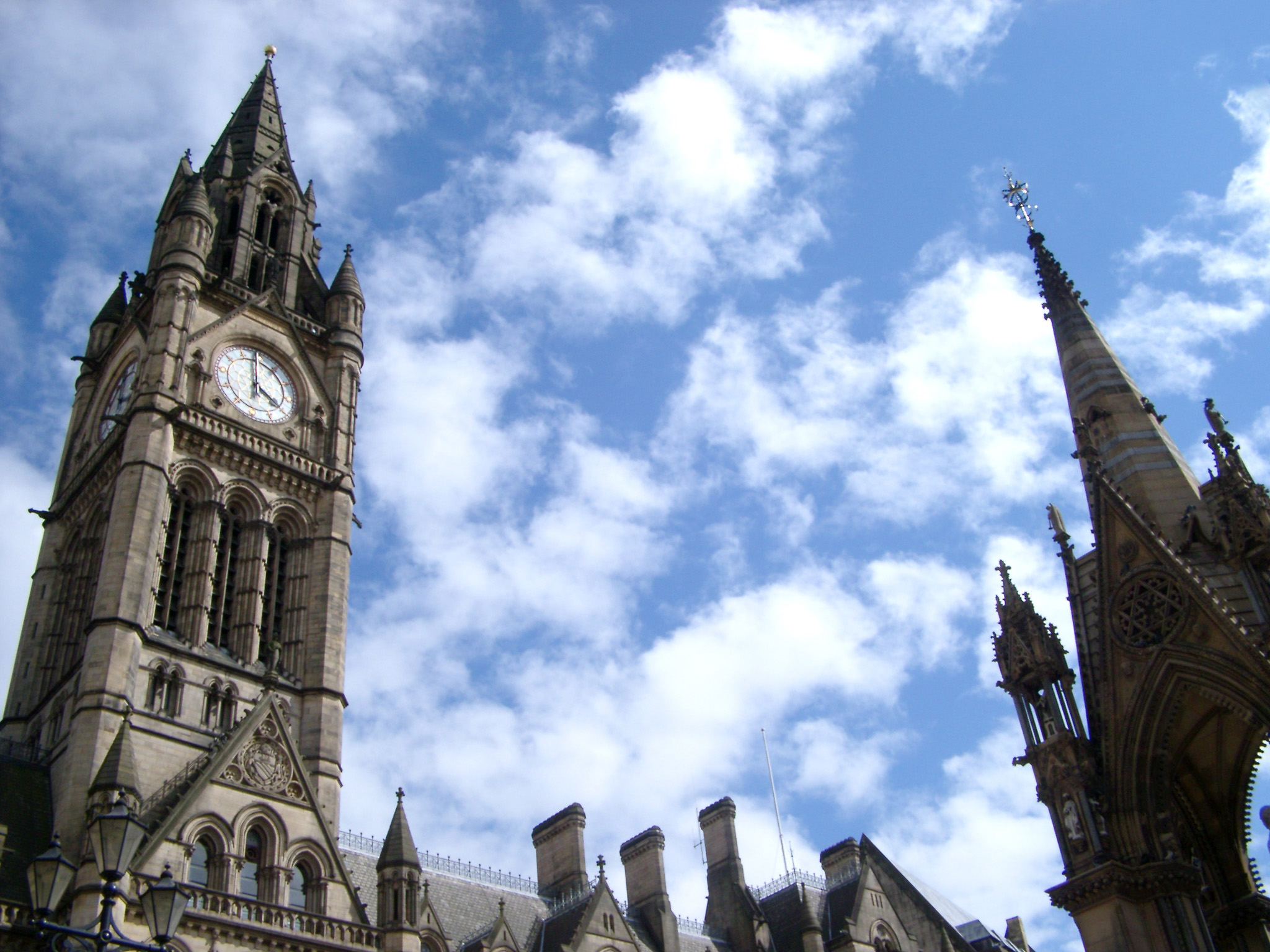 an image of Gothic revival clock tower on the Manchester Town Hall against a cloudy blue sky