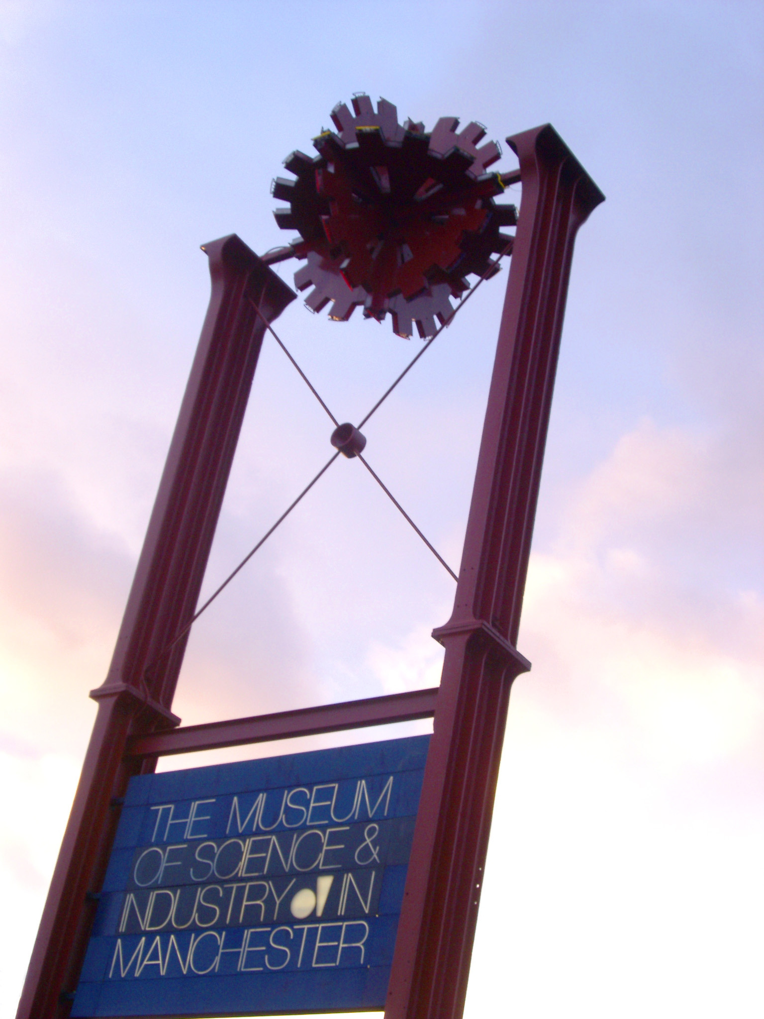 an image of Museum signboard for the Museum Of Science and Industry in Manchester, UK, silhouetted against a delicate pink sunset sky