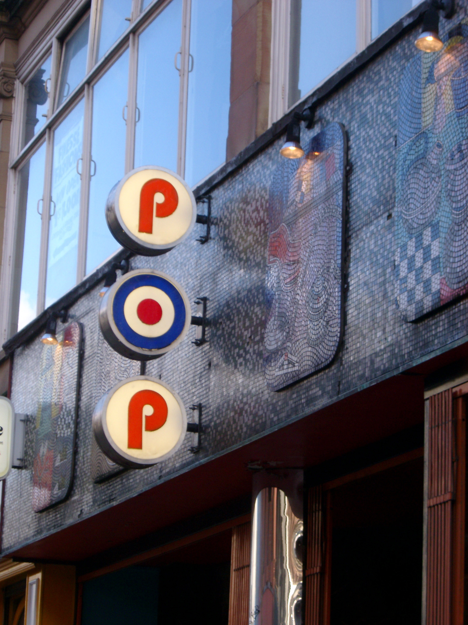 an image of Signage for the Pop Cafe, a 1960s retro vegetarian eatery, on the front of a building amongst decorative tiles