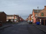 Side street in Moss, Manchester showing the typical red brick architecture, parked cars and a garbage bin