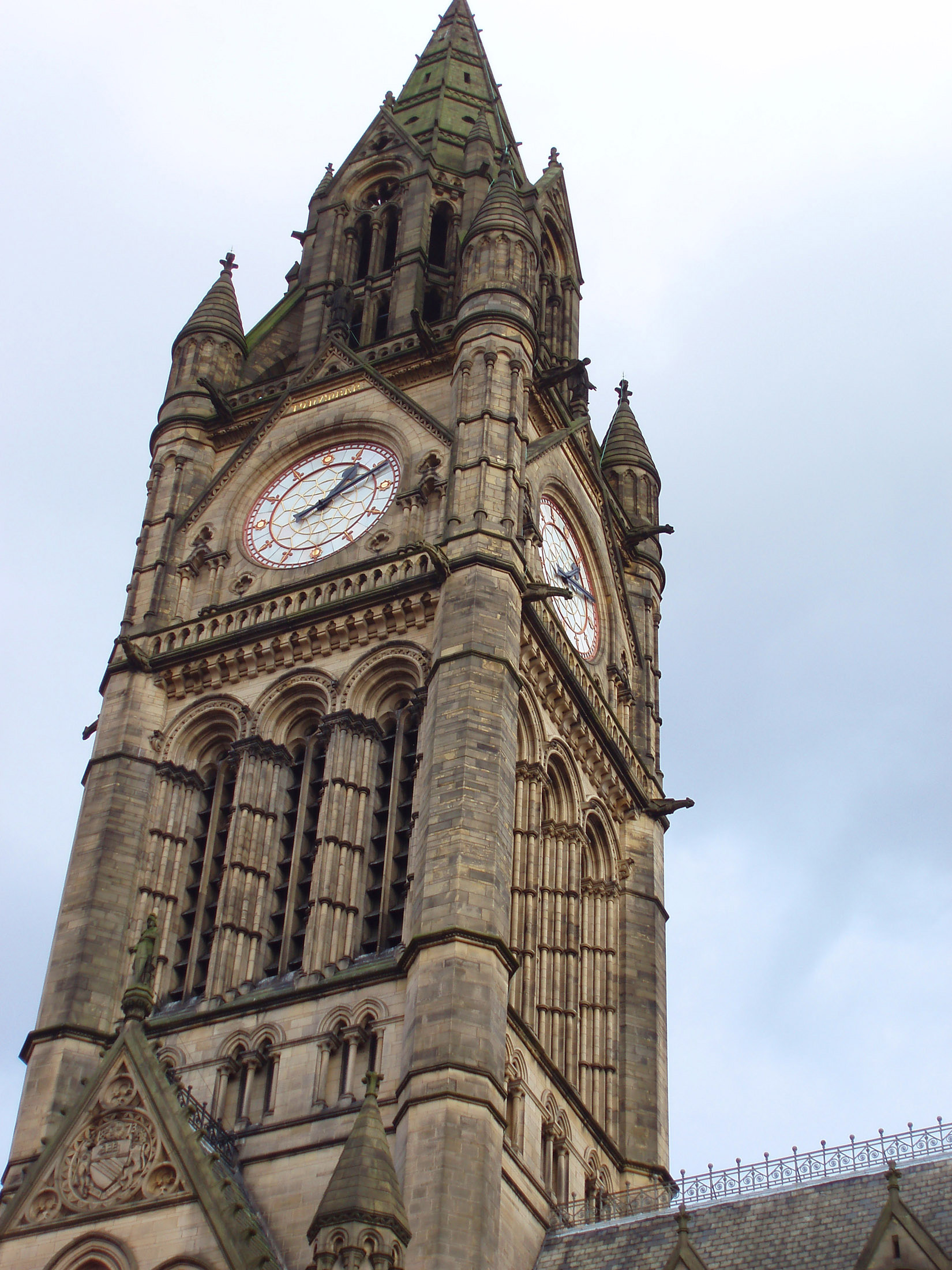 an image of Exterior ornate stone facade of the Gothic revival clock tower on Manchester Town Hall with its four clock faces, Lancashire, UK