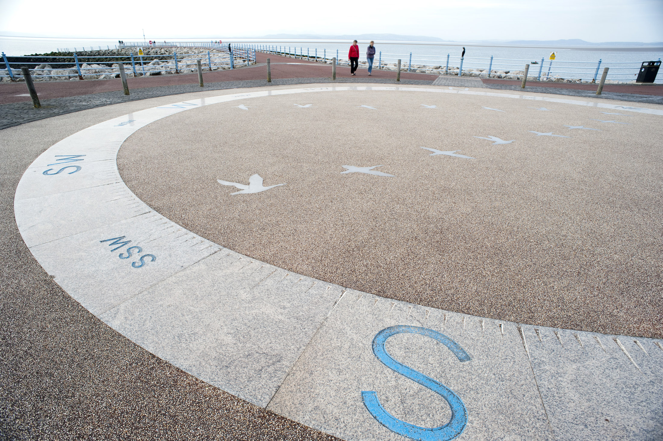 an image of a giant compass set into the pavement breaks up what would otherwise be a quite drab walk along the stone pier