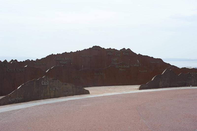 a metal sculpture on morecambe seafront mirrors the mountains and fells of the lake district that can be seen across the bay on a clear day