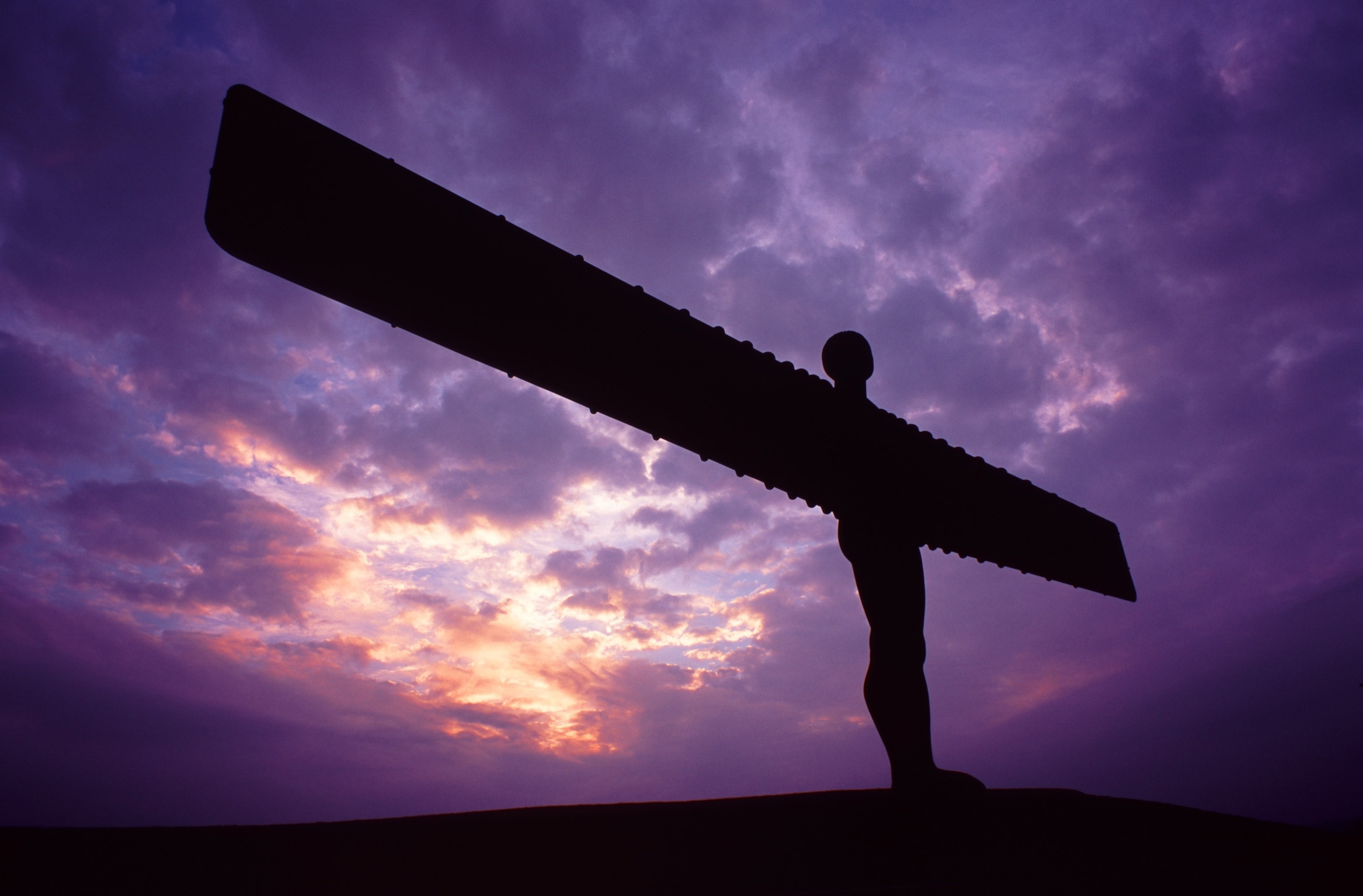 an image of Angel of the North sculpture silhouetted against a colourful purple sky at sunset, Gateshead, Newscastle