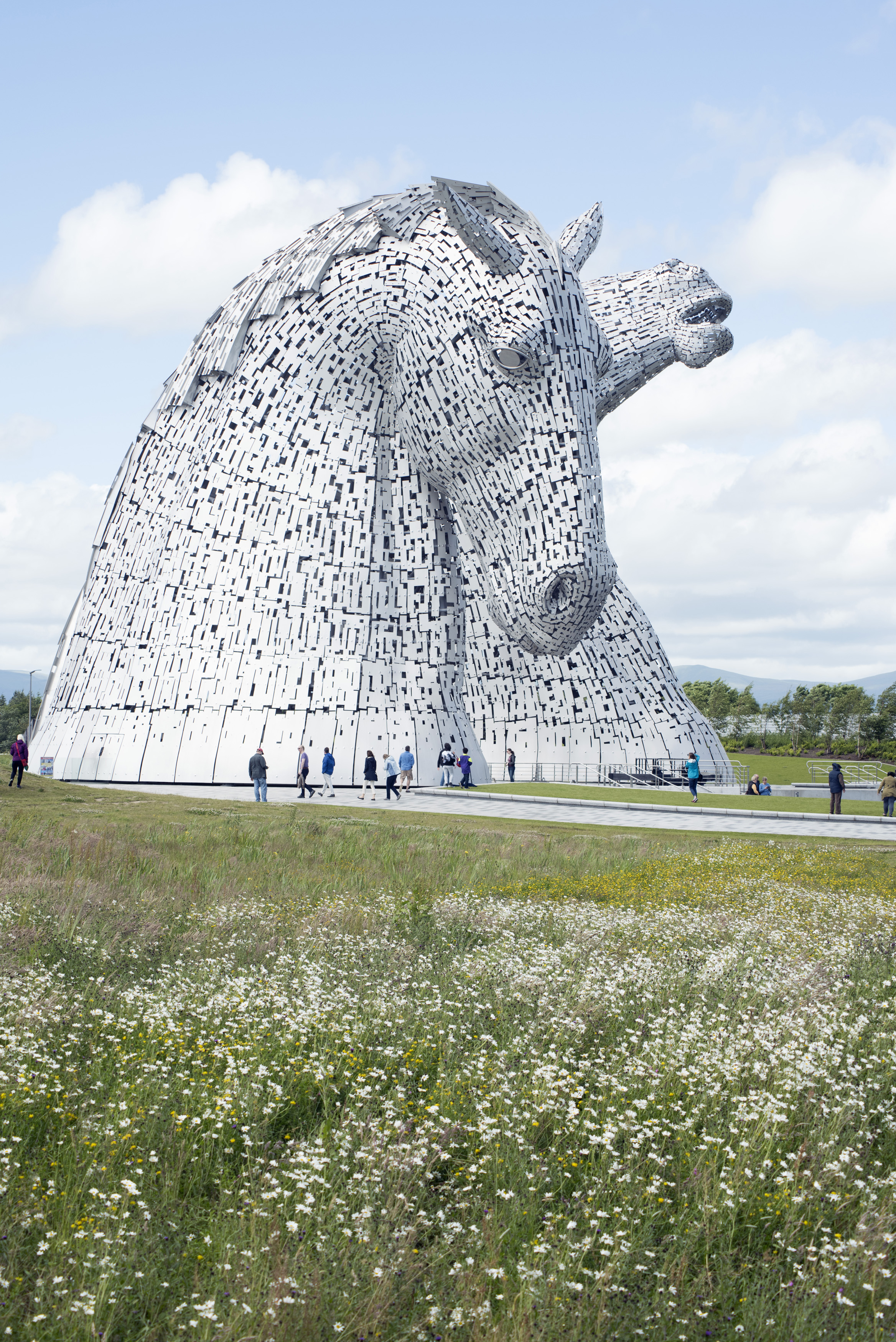 an image of Kelpies horse monuments surrounded by scattered clouds in grassy field at Falkirk, Scotland
