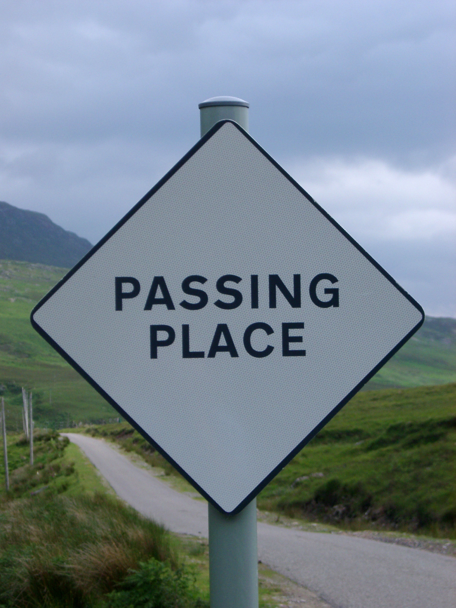 an image of Passing Place roadsign in Scotland on a single lane rural road indicating a safe place for vehicles traveling through the Highlands to pass