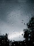 Raindrops beading on a glass window on a dark stormy day in a background concept for the weather or climate