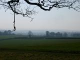 Misty landscape view of lush green English countryside with farmland and pasture and distant trees
