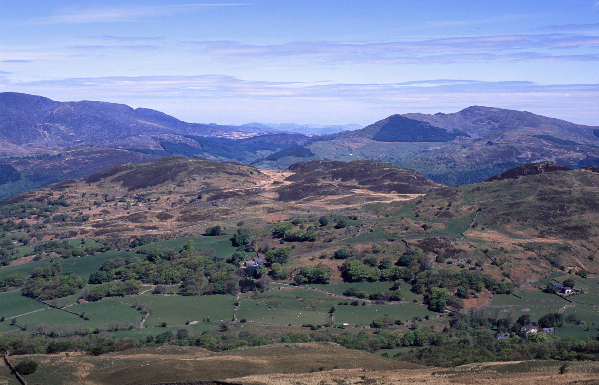 an image of Panoramic Welsh landscape with rolling hills and distant purple mountain ranges under a blue sky