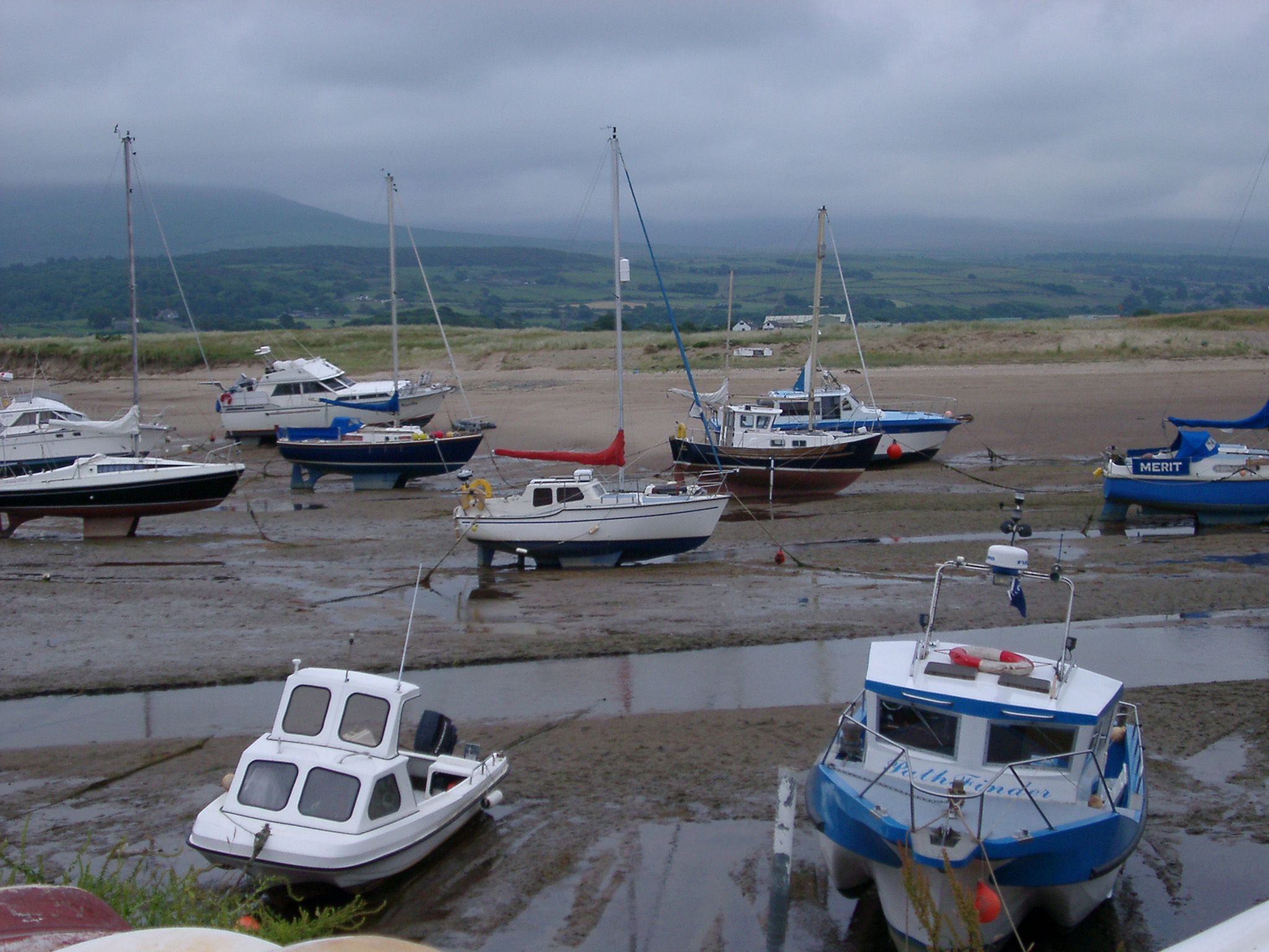 an image of Small fishing boats beached on mud flats in an estuary stranded on the sand by the receding tide on Shell Island