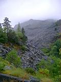 Huge slag heap from slate mining, Blaenau Ffestiniog, slowly being reclaimed by trees and vegetation on a misty rainy day