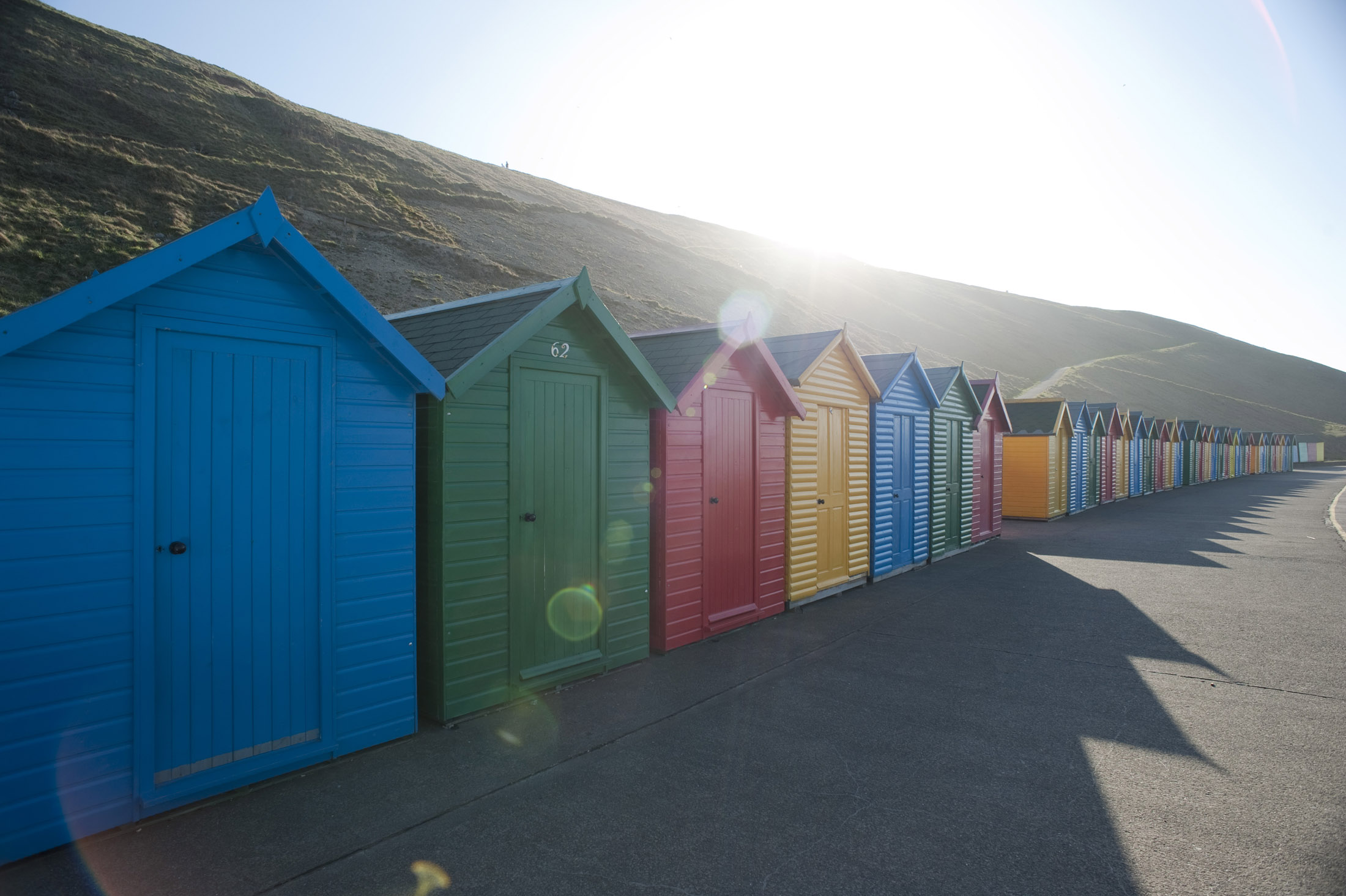 an image of a line of beach huts on the shore at whitbys west cliff