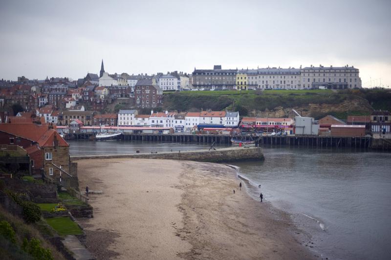 a view of tate hill sands and whitbys west cliff across the harbour on a wet day