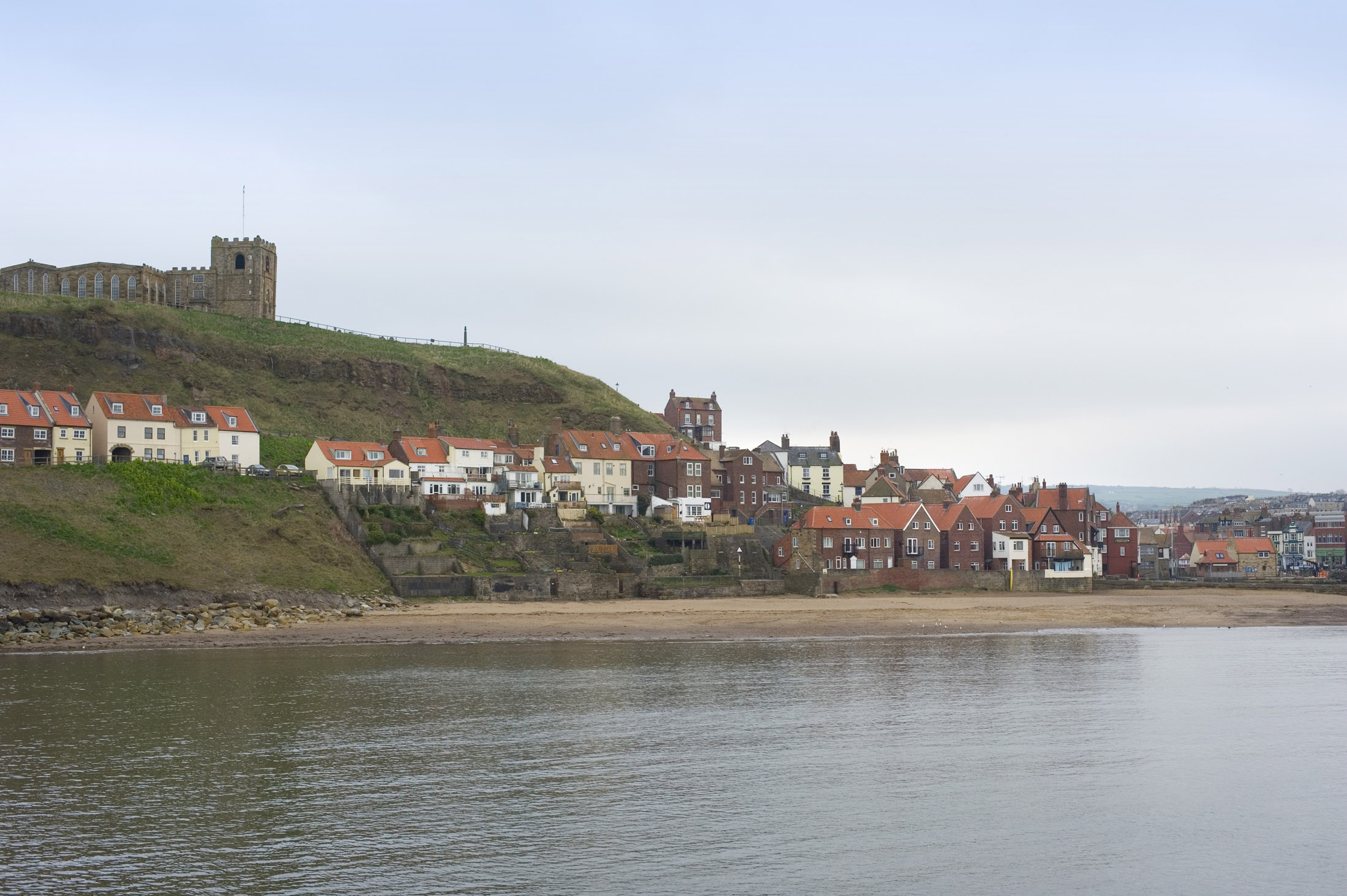 an image of st marys church on top of the east cliff and below the houses on tate hill and tate sands, whitby lower harbour