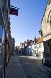 early morning sun shines on the quaint shops of church street, whitby