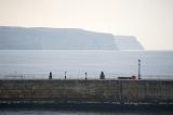 a view across one of the stone piers at whitby an the coastal headlands beyond