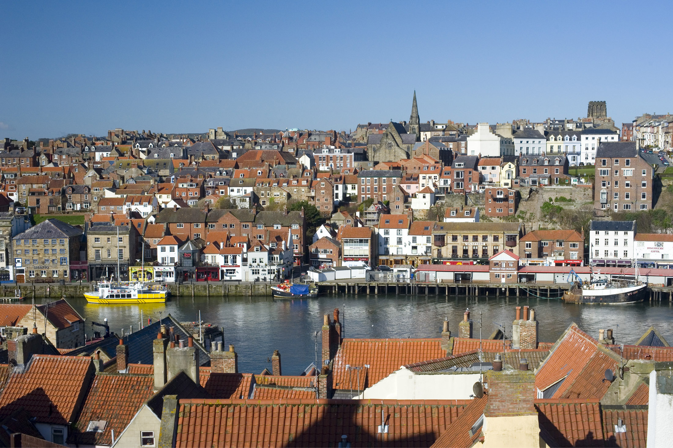 an image of the town of whitby viewed from the east cliff looking down on the rooftops