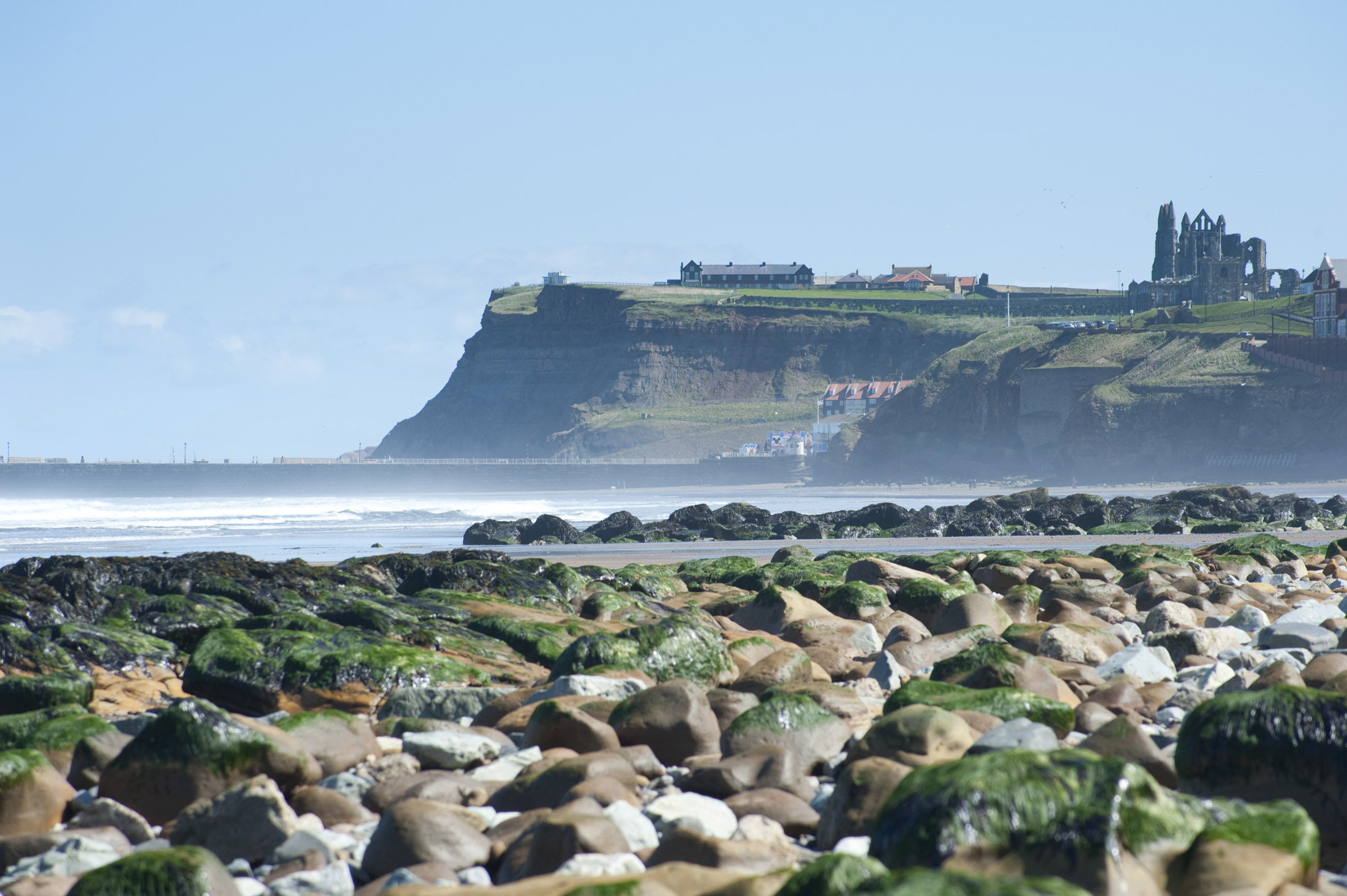 an image of headland to the east of whitby with the landmark abbey ruins on top