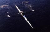 Overhead view of a man practising sculling in a single boat rowing along a river with water splash off the oars