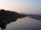 Tranquil misty estuary at dusk with the forest and distant mountains mirrored in the calm water